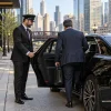 Male business traveler entering an unbranded black sedan in downtown Chicago