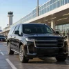 Male chauffeur beside an unbranded black SUV at Midway Airport pickup