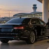 Chauffeur holding open the door of a black sedan at O'Hare Airport